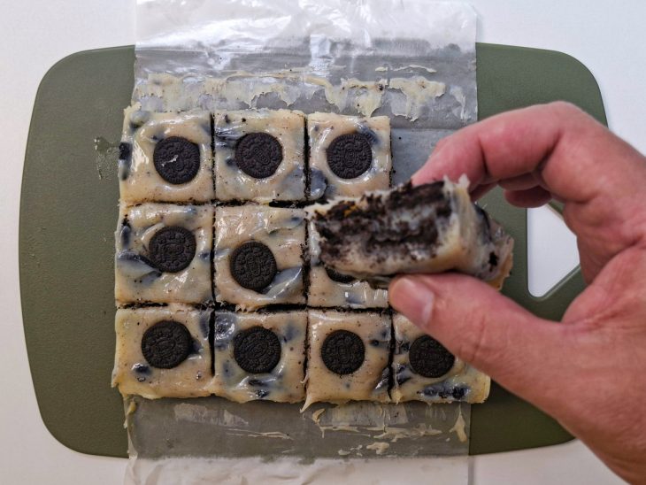 Doce já firme sendo cortado em pedaços quadrados.