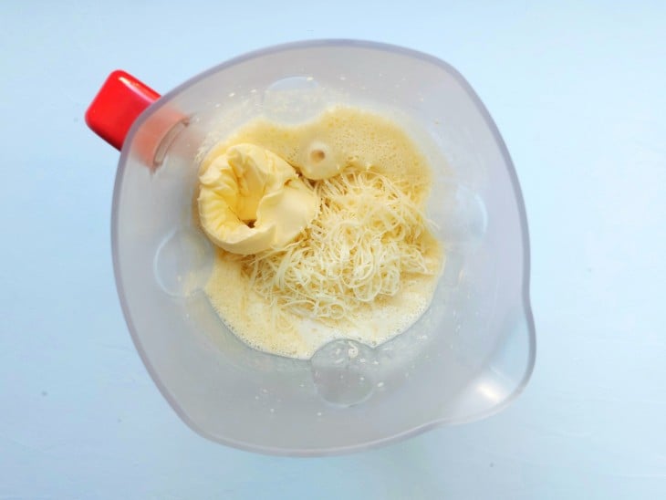 Manteiga, parmesão, fubá e fermento adicionados à mistura do liquidificador.