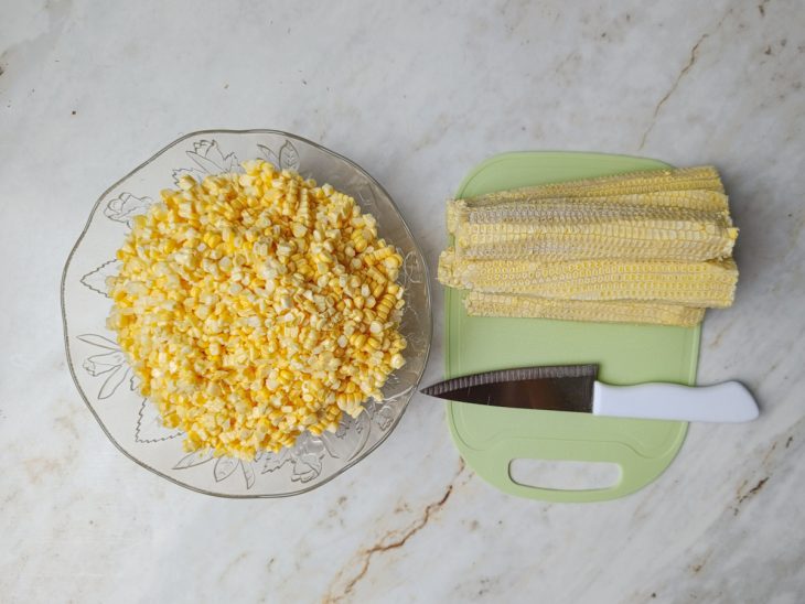 Espigas limpas com milhos reservados numa tigela redonda de vidro.