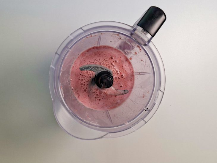 Leite e morangos batidos no liquidificador.