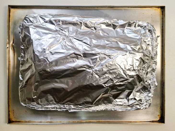 panceta de porco coberta com papel alumínio para primeira etapa de assar.