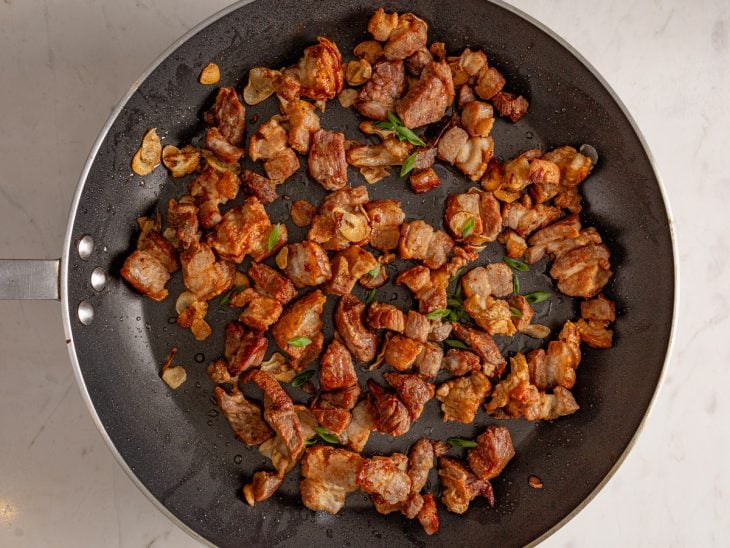 Uma frigideira com panceta e temperos fritos.