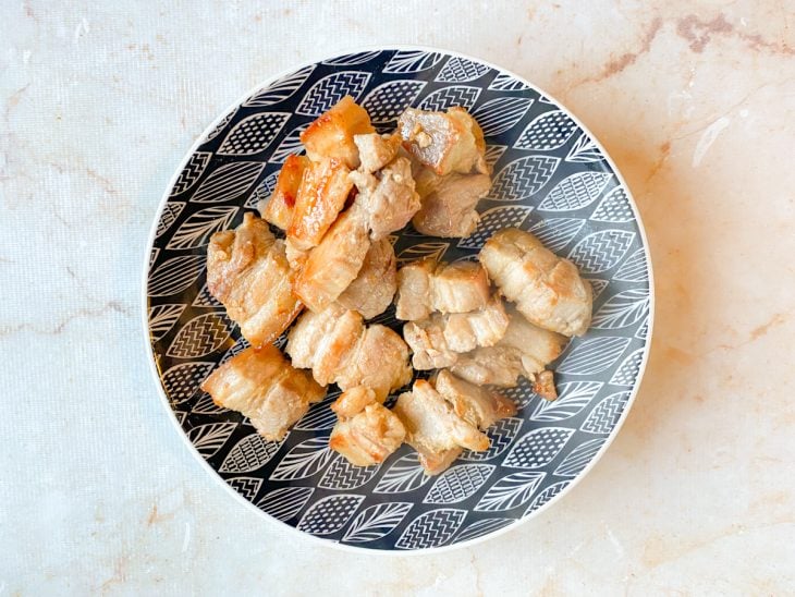 Pedaços de panceta selados reservados em um prato.