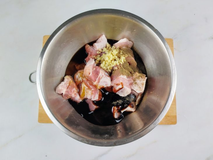Alho, gengibre, shoyu, molho de ostra, mel, pimenta-do-reino e mirin adicionados ao recipiente com os cubos de panceta.