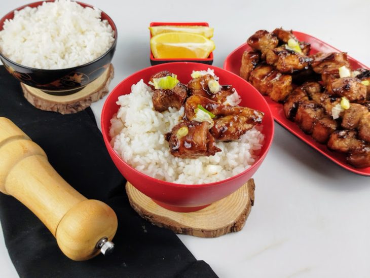 Porção de panceta em um bowl com arroz e cebolinha.