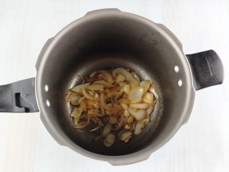 Na panela de pressão, o alho e a cebola dourados.
