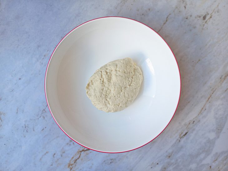 Em uma tigela, a semolina, a farinha de trigo, o óleo e o sal misturados em uma massa.