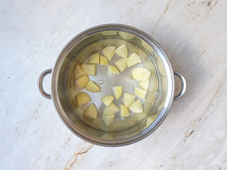 Na panela com água, as batatas cozidas.