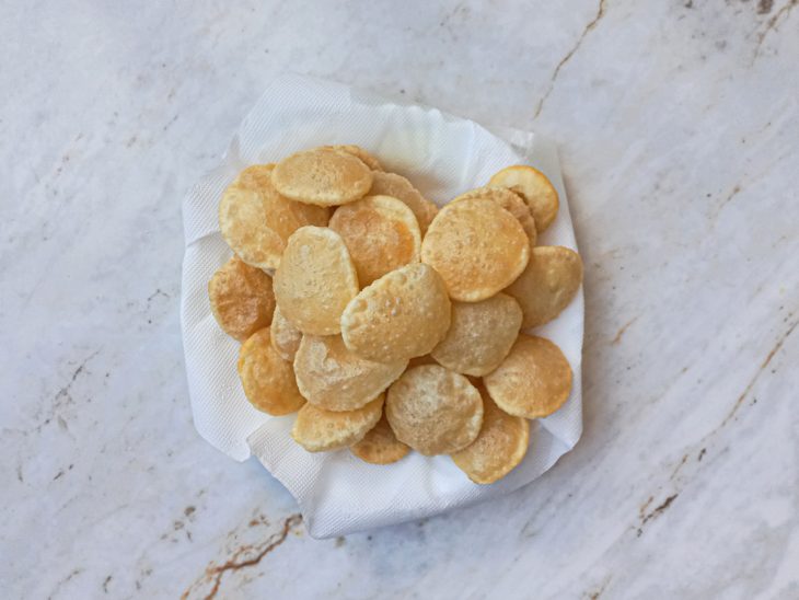 Escorrendo em papel toalha, as puri saídas da panela de fritura.