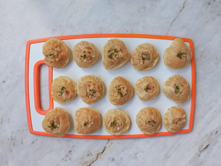 Numa tábua, as puri sendo recheadas com a pani.