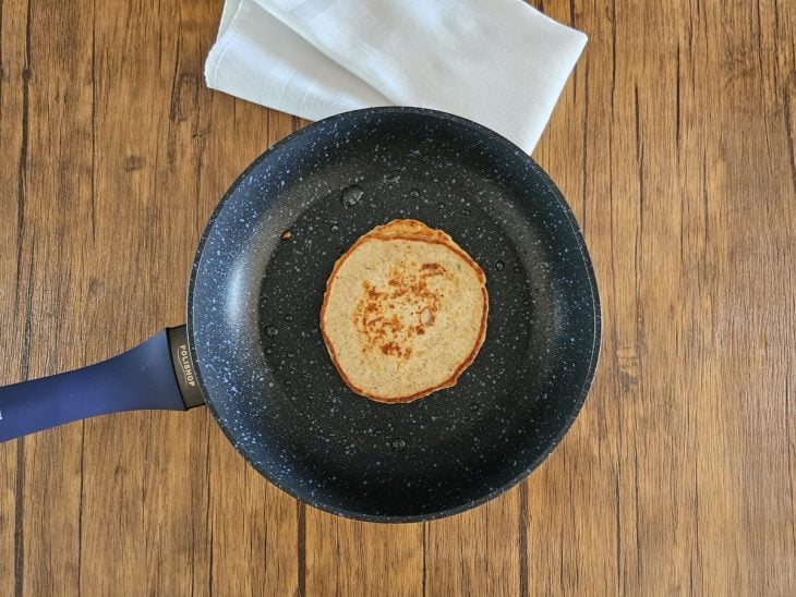 Uma frigideira contendo uma porção da massa da panqueca sendo frita.