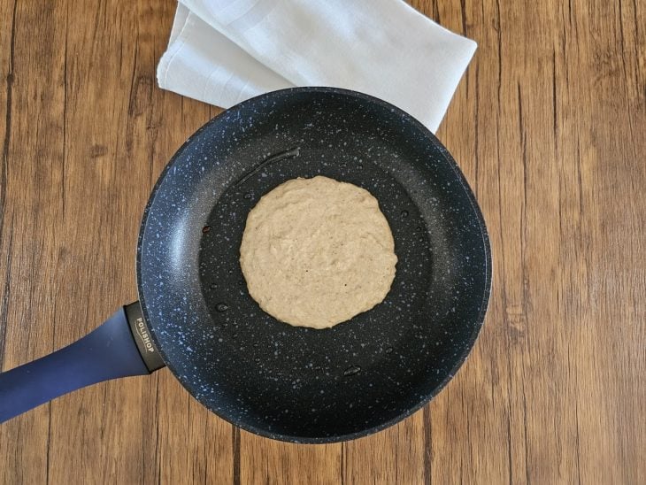 Uma frigideira contendo uma porção da massa da panqueca sendo frita.