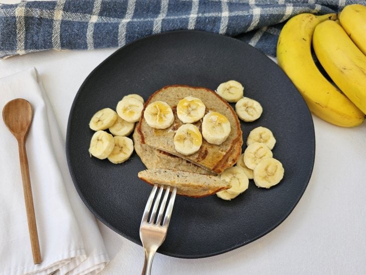 Um prato contendo rodelas de banana e panqueca de banana fit com aveia.
