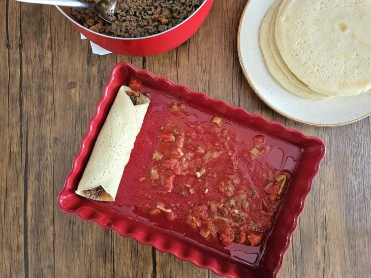 Um refratário forrado com molho vermelho contendo uma panqueca de carne moída.