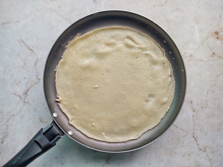 Porção da massa cozinhando na frigideira.