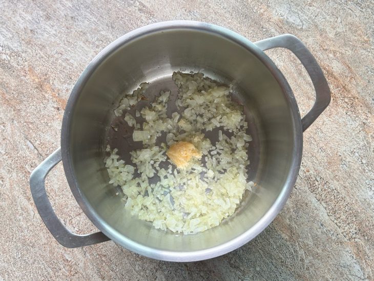 Alho e cebola refogando em uma panela com azeite.