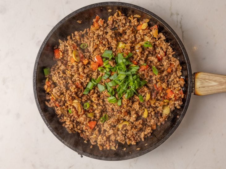 Tomate, azeitona e cheiro-verde adicionados na frigideira.