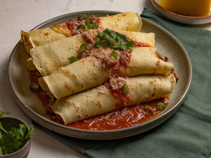 Panqueca fácil de carne moída finalizada com molho de tomate e queijo parmesão, pronta para consumo.