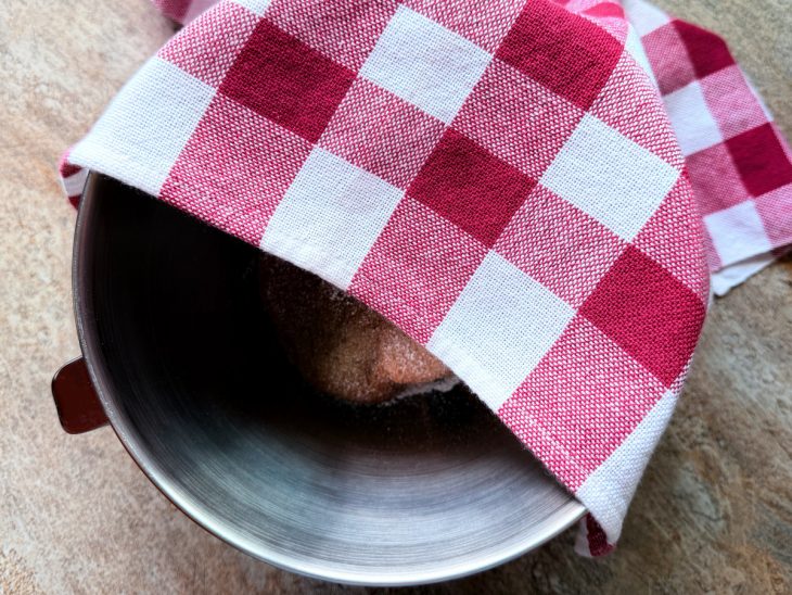 Massa na tigela, coberta com pano de prato.