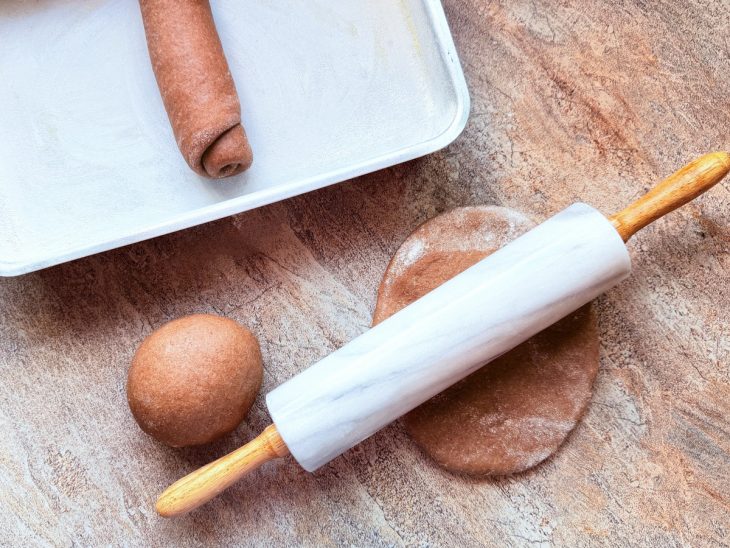 Bolinhas de massa sendo abertas com um rolo.