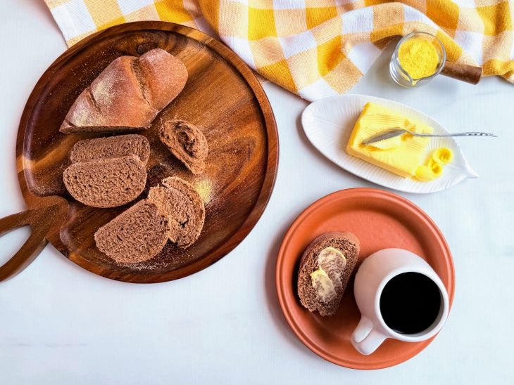 Pão cortado, fatias servidas com manteiga e café.