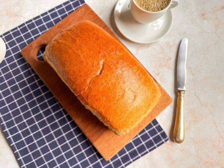 Pão pronto, servido em tábua, café acompanhando.