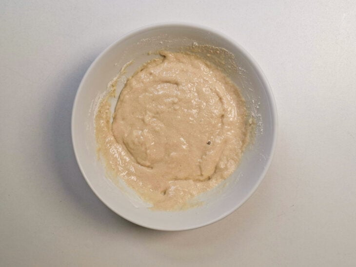 Tigela com a pasta de fermento coberta com plástico filme na mesa.