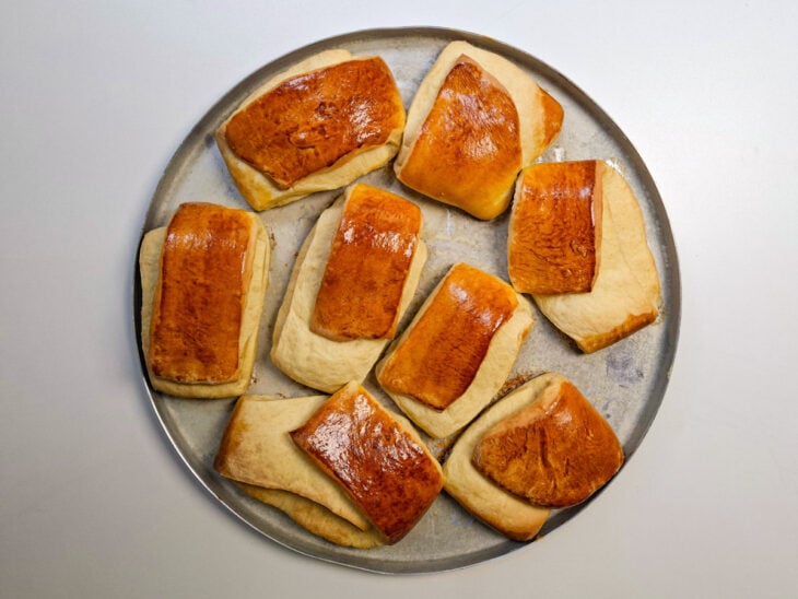 Assadeira retirada do forno com os pães carteira crescidos e dourados.