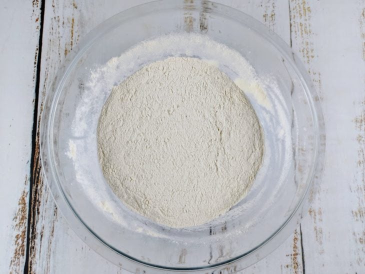 Farinha de trigo, açúcar, sal e fermento em uma tigela de vidro.