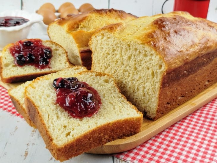 Pão de liquidificador pronto para consumo e algumas fatias dele com geleia de morango.