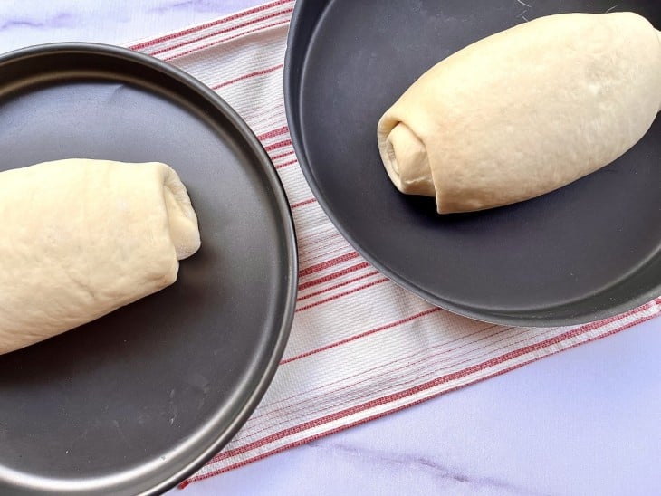 Duas formas com os pães crus.