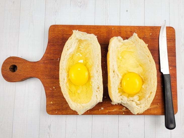 Um pão francês cortado com ovos crus.