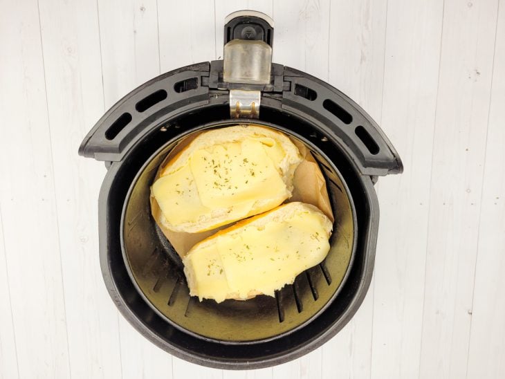 Pão francês com ovo e queijo na airfryer a dourar.