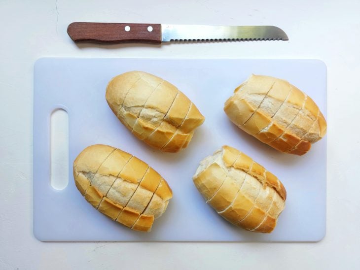 Tábua com um pão cortado e uma faca ao lado.
