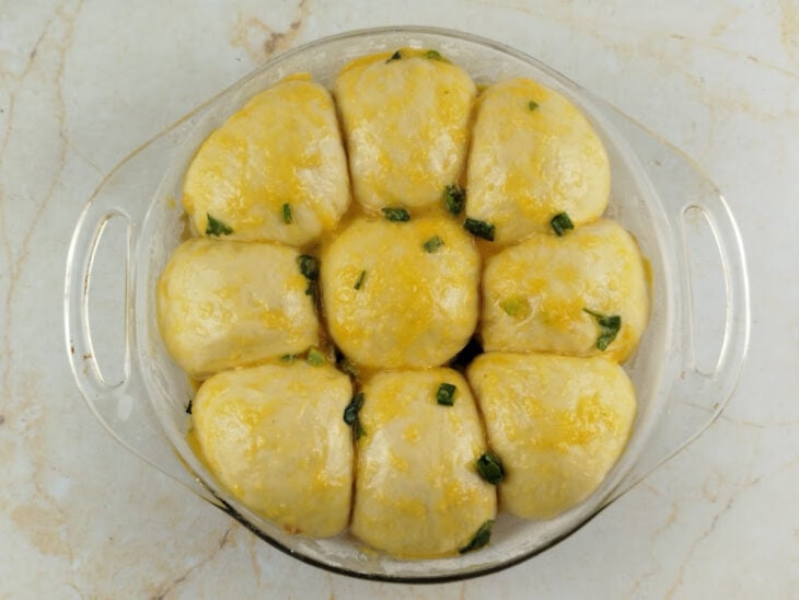 Pasta de alho sendo pincelada generosamente sobre as marcações e por todo o topo do pão.