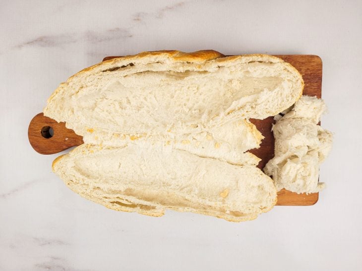 Uma tábua contendo um pão italiano aberto.