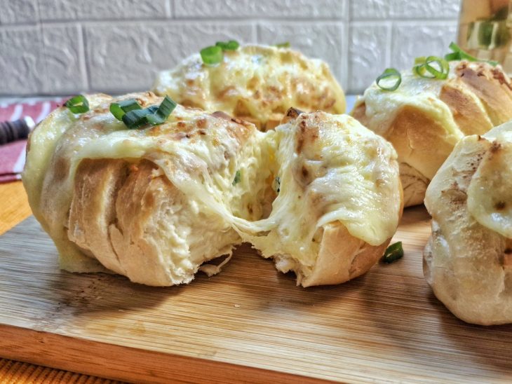 Pão de alho finalizado com queijo e cebolinha pronto para consumo.
