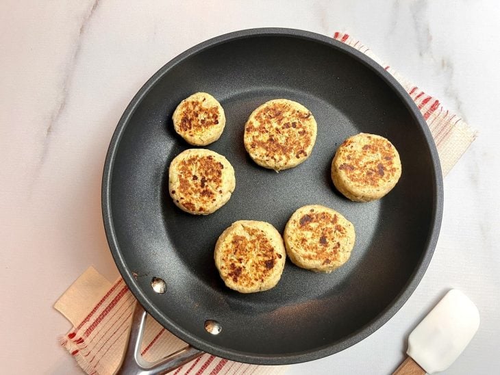 Uma frigideira com alguns pãezinhos sendo preparados.