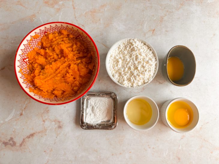 Ingredientes separados na bancada com batata-doce cozida e ovo quebrado.