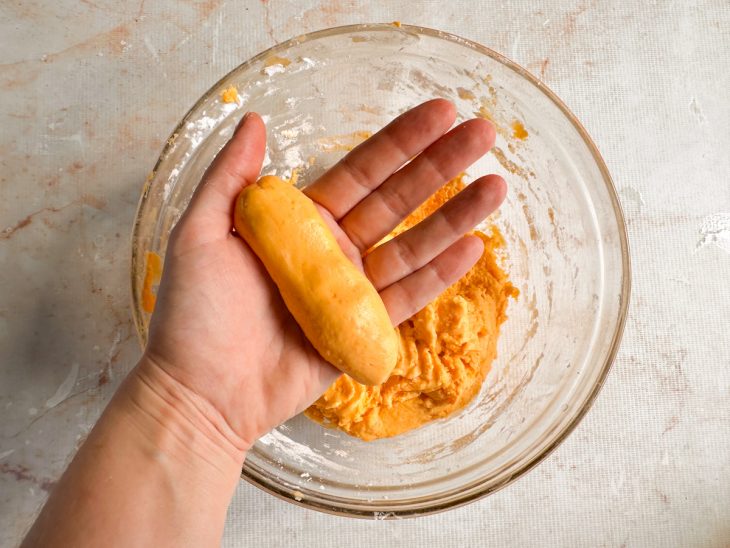 Porções da massa sendo modeladas em formato de mini pães.