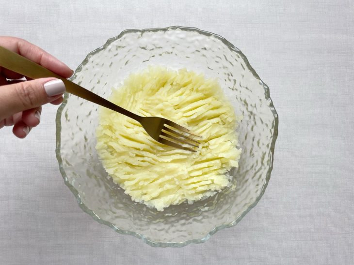 Batatas cozidas sendo amassadas com garfo.