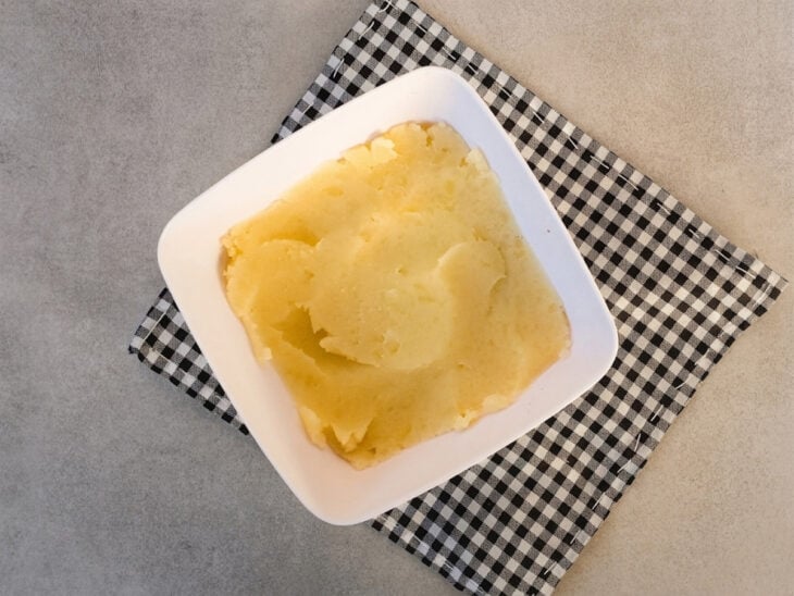 Batatas cozidas sendo amassadas até formar um purê liso.