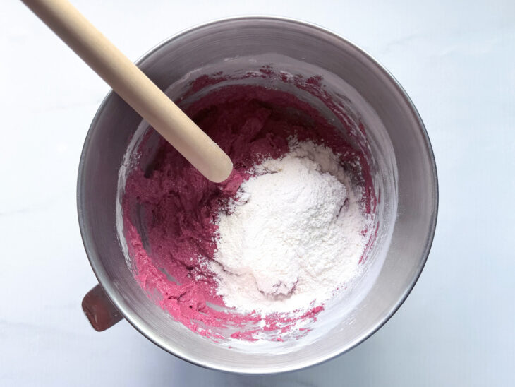 Massa recebendo farinha aos poucos e sendo misturada até ganhar consistência.