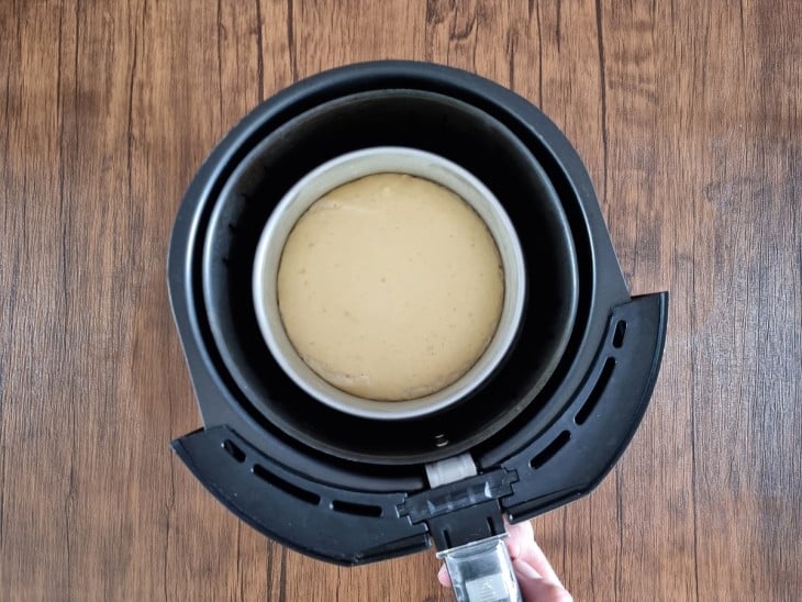 A cesta da airfryer com a forma com o pão cru com dobro de tamanho.