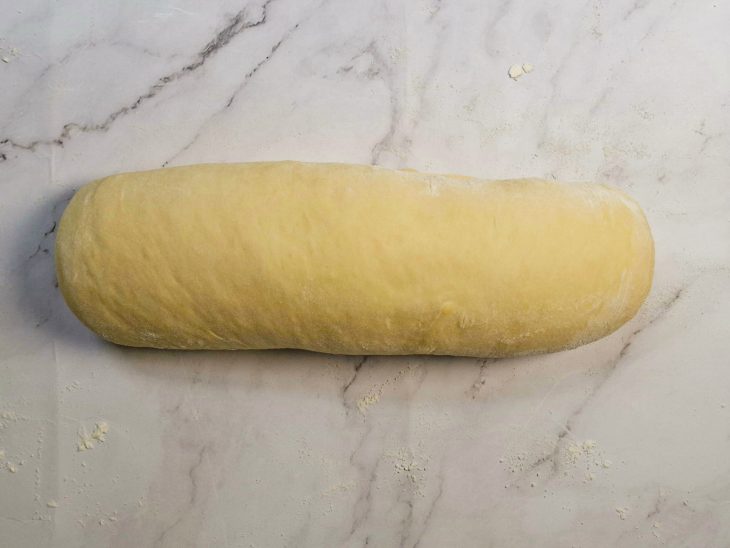 Massa sendo enrolada formando um cilindro.