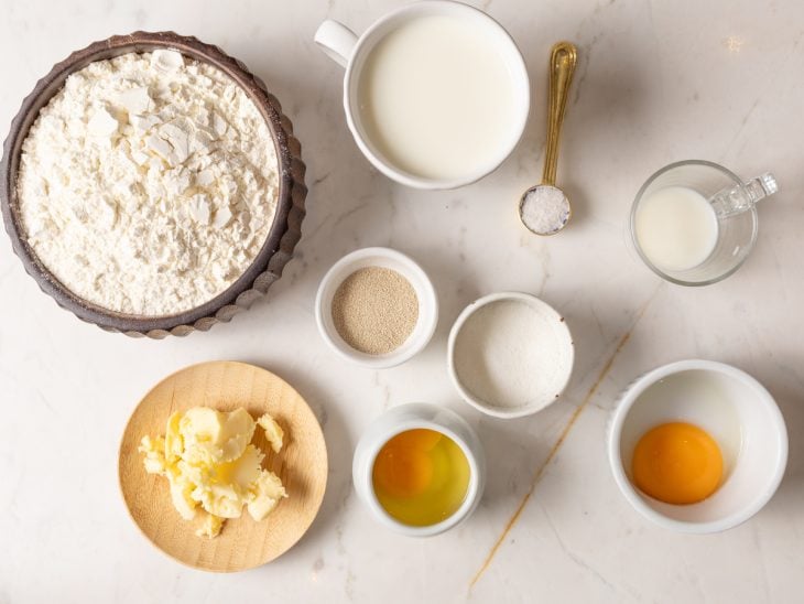 Todos os ingredientes para fazer o pão de leite na air fryer dispostos em uma bancada.