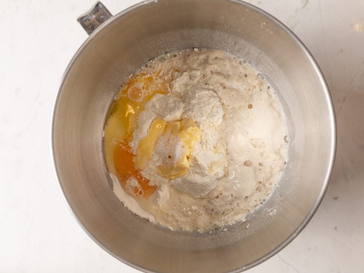 Tigela maior com ovos, farinha de trigo, manteiga e sal adicionados a mistura.