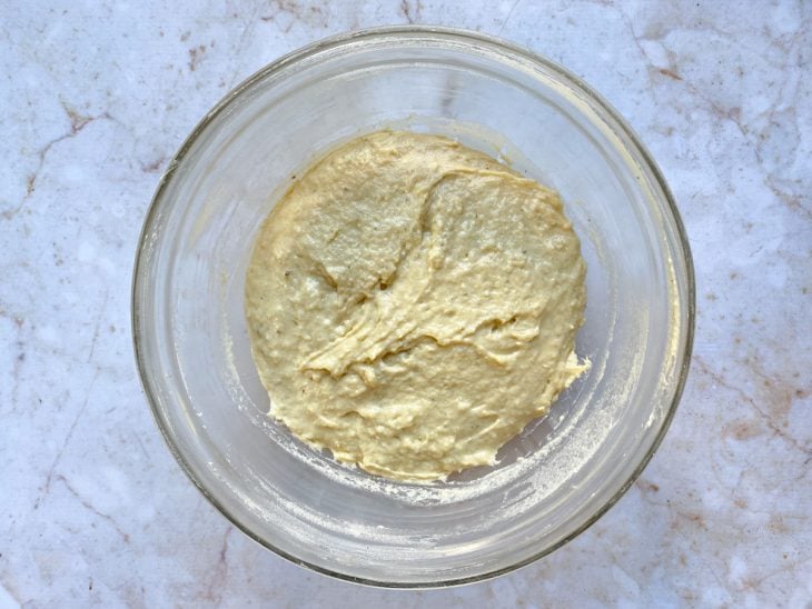 U recipiente contendo a massa crua do pão e farinha.