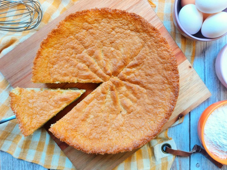 Um bolo pão de ló com uma fatia sendo retirada.