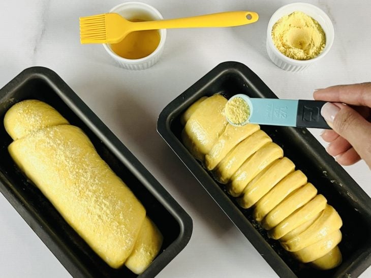 Pães pincelados com manteiga e polvilhados com fubá.